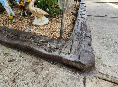 Continuous landscape concrete curbing with a realistic rustic wood-grain texture and dark brown coloring
